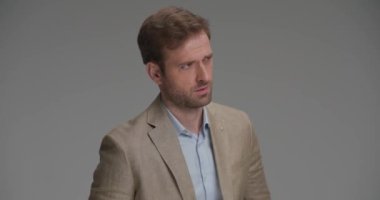 İş adamı aşağı bakıyor, başka tarafa bakıyor, takım elbisesini ayarlıyor ve sert bir tavırla poz veriyor.