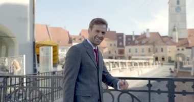 Şehrin dışında yürürken gülümseyen, parmağıyla tapınağı işaret eden ve askeri selam veren mutlu bir gencin video projesi.