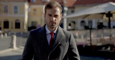 Genç yakışıklı işadamı kameraya bakıyor sonra da dışarı bakıyor.