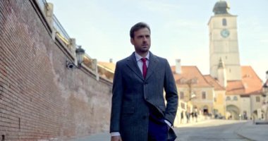 İş adamı cepte bir el çantası ve şehirde bir çantayla poz veriyor.