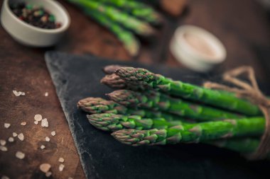 Tahta bir masadaki tahta bir helikopterin tepesindeki taze kuşkonmaz demetinin yakın plan fotoğrafı.