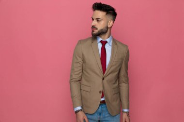 Çekici bir iş adamı pembe arka planda poz veriyor.
