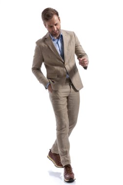 Mutlu iş adamı yön değiştiriyor, bir elini cebinde tutuyor ve beyaz arka plana gülümsüyor.