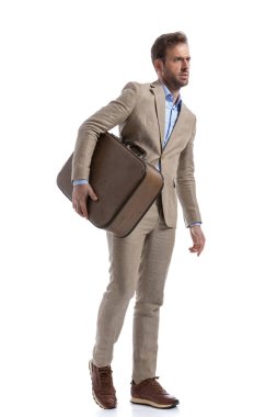 Seksi bir iş adamının beyaz arka planda yürüdüğü ve elinde bir evrak çantası tuttuğu bir kenar görüntüsü.