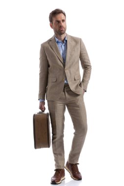 Yakışıklı iş adamı bir eli cebinde, diğer eli çantasıyla yürüyor.