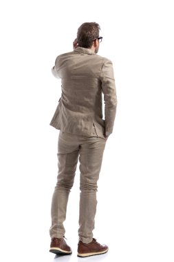 Kafasını kaşıyan bir iş adamının arkadan görünüşü beyaz arka plana karşı en iyi stratejiyi düşünüyor