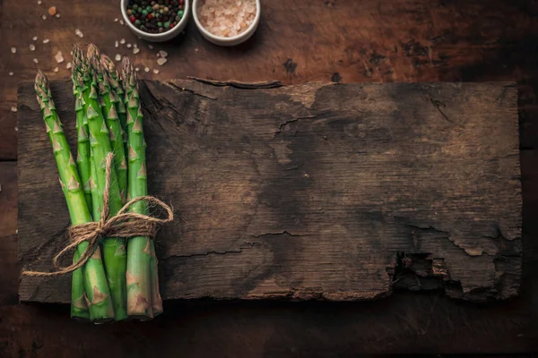 Sağlıklı yaşam konsepti: Köy ahşabının tepesindeki eski bir tahta parçasında taze kuşkonmaz demeti.