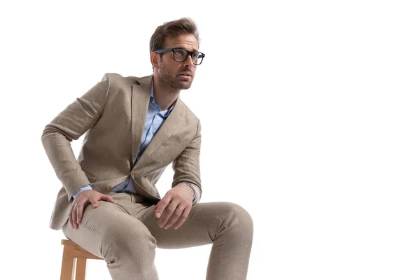 性感的生意人坐在椅子上 戴着眼镜 望着外面的白色背景 — 图库照片