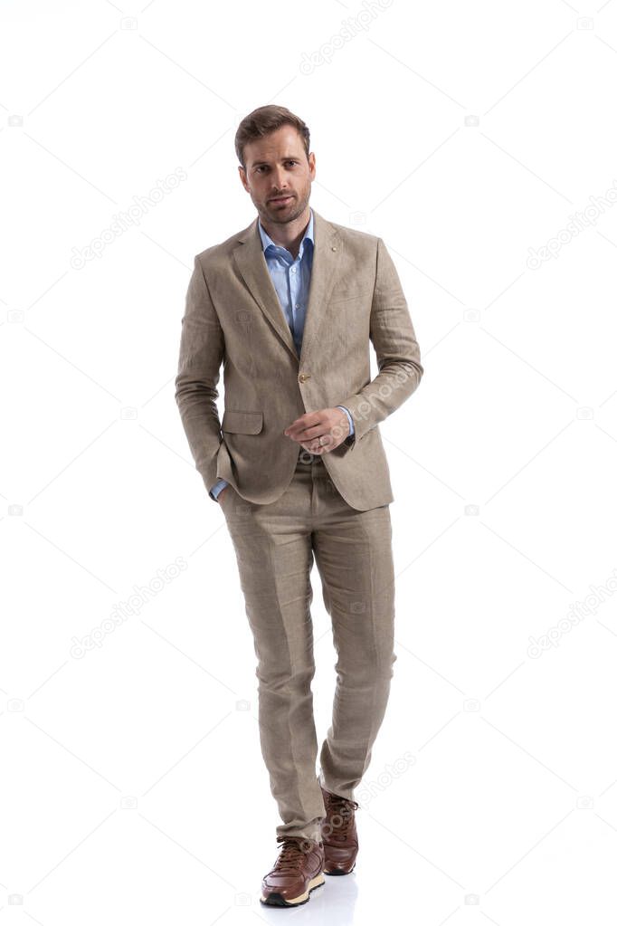 young handsome businessman walking towards the camera with one hand in pocket against white background