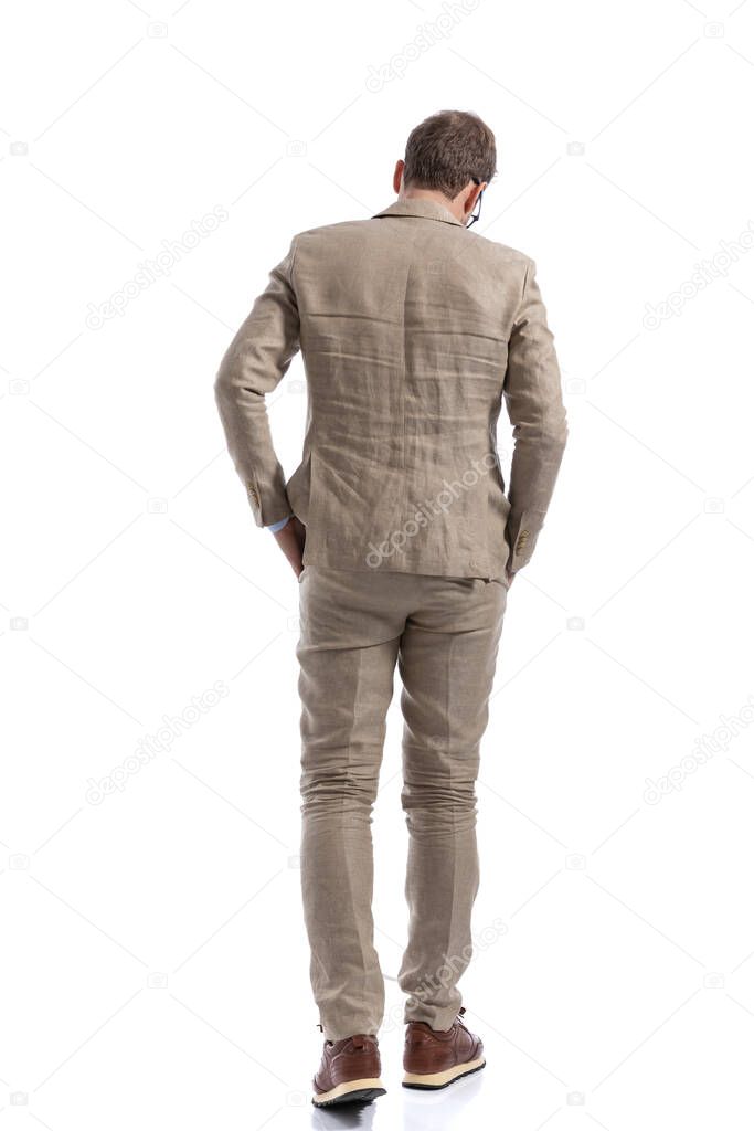 rear view of a businessman walking away from the camera with his hands in pockets