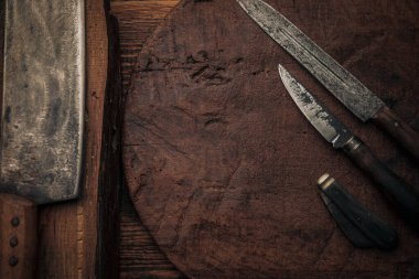 Paslı eski bıçakların yanında küçük bir çakı ve eski ahşap kesme tahtalarının üzerinde fotokopi alanı olan bir satır.