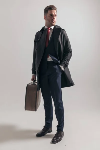 雅致的男子 身穿西服 手提着手提箱 站在工作室灰色背景的一边 — 图库照片