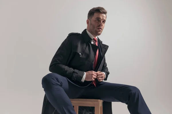 Sexy Elegancki Biznesmen Patrząc Stronie Rozpinania Garnitur Siedząc Przed Szarym — Zdjęcie stockowe