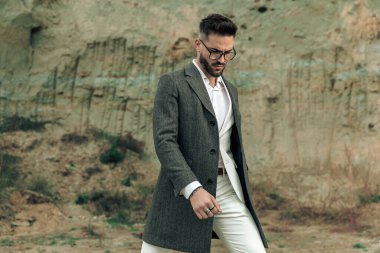 Gözlüklü yakışıklı sakallı adamın portresi aşağı bakıyor ve doğada poz veriyor.