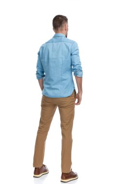 40 'lı yaşlarda bir adam arka plan pozisyonunda duruyor ve stüdyoda beyaz arka plana bakıyor.