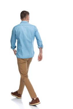 Arka planda kot pantolonlu ve Chino pantolonlu bir adam stüdyoda beyaz arka planda yürüyordu.