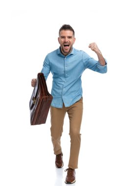 Kazanan adam bavulunu havaya kaldırdı ve çığlık atarken ve stüdyoda beyaz arka planda kutlama yaparken zaferin tadını çıkarıyor.