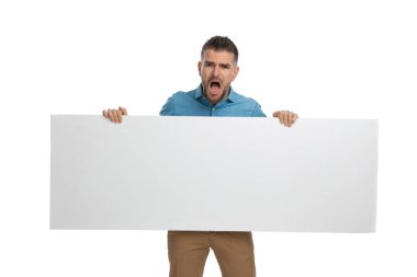 Boş tahtayı tutan ve sunan, ağzı açan ve beyaz arka planda şok olan genç bir adamı gücendirdim.