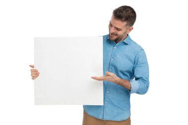 Mavi kot pantolonlu mutlu orta yaşlı adam elinde boş ilan panosu, gülümsüyor ve beyaz arka planda poz veriyor.