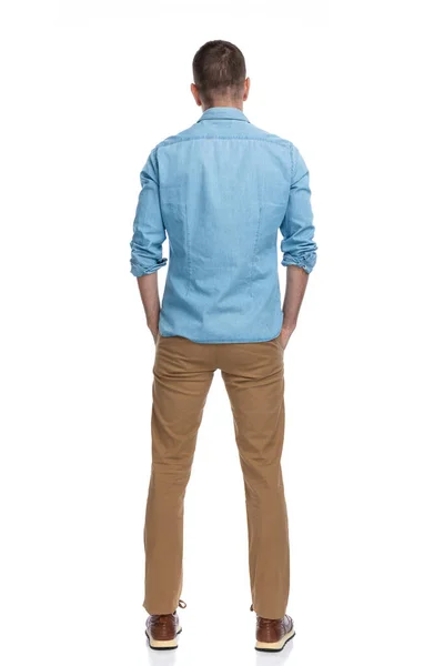 白い背景にポケットに手を入れたカジュアルなデニムシャツの男の後ろ姿 — ストック写真