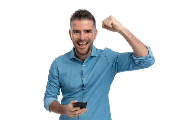 Podekscytowany Młody Człowiek Trzyma Telefon Czyta Dobre Wieści Świętuje Zwycięstwo — Zdjęcie stockowe
