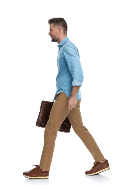 お金を持ってスーツケースを持って白い背景に隔離された歩くカジュアルな髭男の全身像 — ストック写真