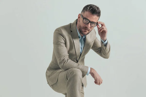 Homem Sério Com Barba Segurando Cotovelo Joelho Fixando Óculos Posando — Fotografia de Stock