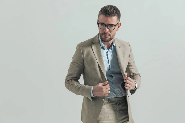Portrait Unshaved Middle Aged Businessman Glasses Grey Background Arranging Suit — Stock Photo, Image