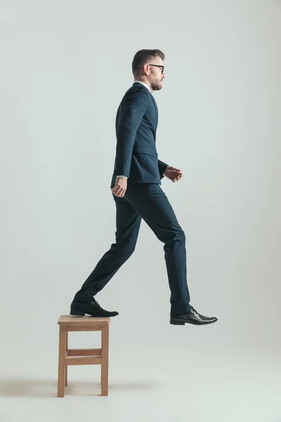 Πλαϊνή Όψη Του Όρθιου Επιχειρηματία Κοστούμι Που Πατάει Ξύλινη Καρέκλα — Φωτογραφία Αρχείου