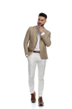 Yakışıklı iş adamı nazikçe çenesine dokunuyor, başka yere bakıyor, bir eli cebinde yürüyor.