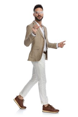 Kameraya bakıp beyaz arka planda yürüyen bir iş adamının yan görüntüsü.