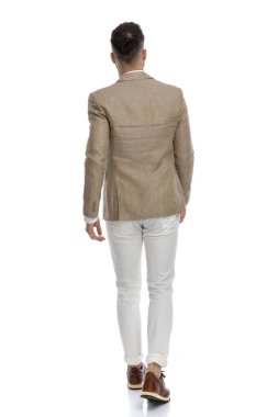 Genç iş adamı kameradan uzaklaşıyor ve beyaz arka planda güzel bir takım elbise giyiyor.