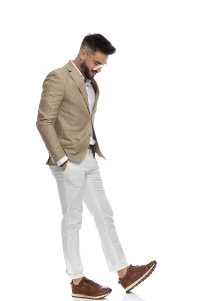 白い背景を背景に腕をポケットにして靴の先を見ているハンサムなビジネスマンの — ストック写真