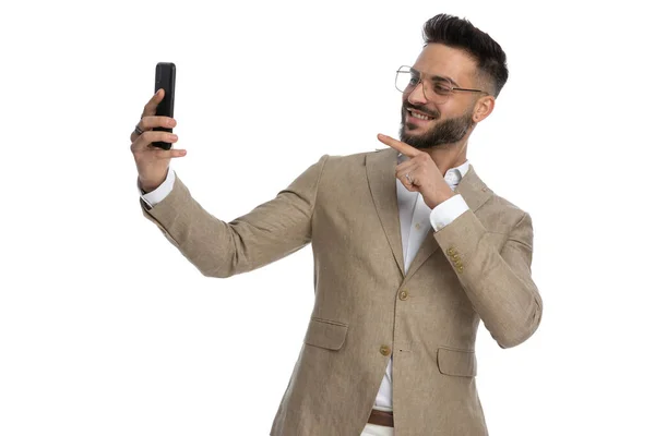ビデオ通話で誰かと話をしながら電話を指しているハンサムなビジネスマン — ストック写真