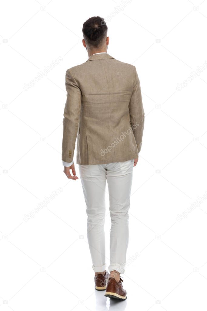young businessman walking away from the camera and wearing a nice suit against white background