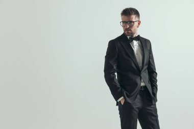 Çekici manken gözlük takıyor, ellerini cebine sokuyor ve başka tarafa bakıyor. 