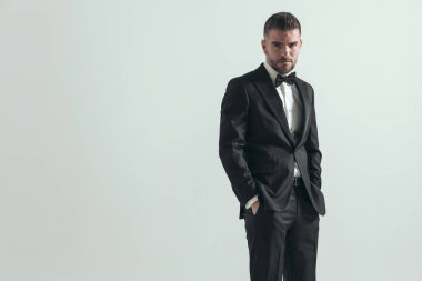 Saçları ağarmış yakışıklı bir işadamı ellerini cebinde tutuyor ve kameraya bakıyor.