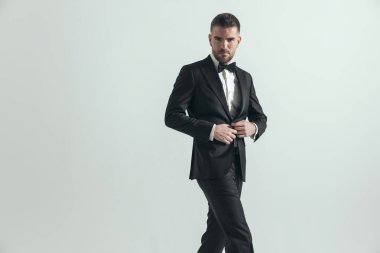 Yüzünde derin bir ifade olan seksi iş adamı ceketini kapatıyor, bacak bacak üstüne atıyor ve poz veriyor. 