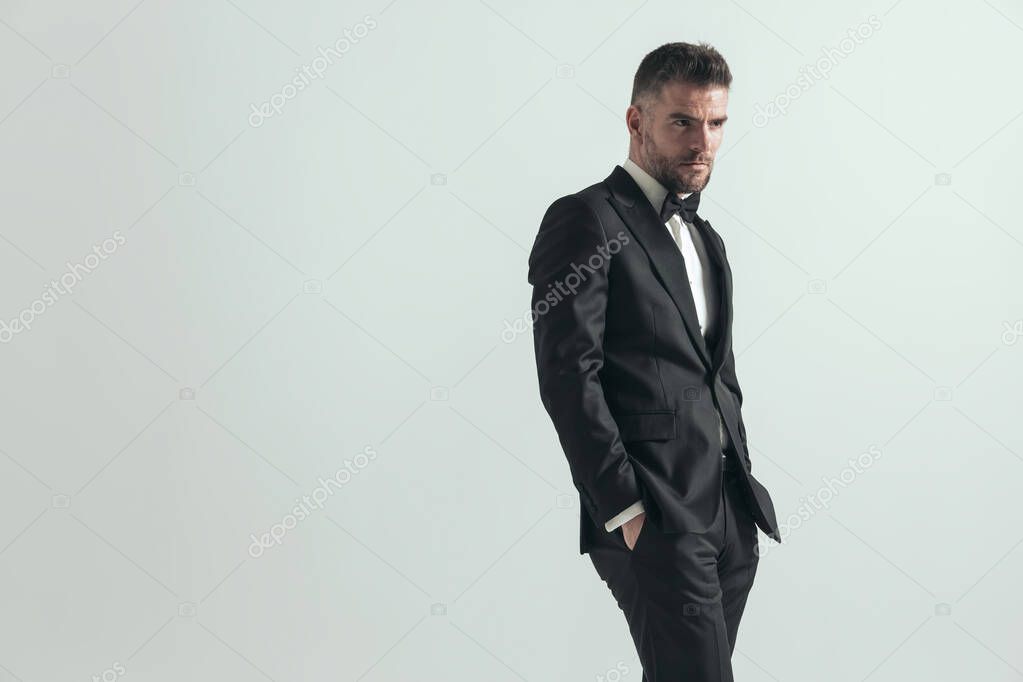 tough businessman looking away with a serious look on his face and holding his hands in pockets