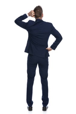 Bir iş adamının tek eliyle başını kaşıması ve bir elini beline koyup önemli bir kararı düşünmesi.