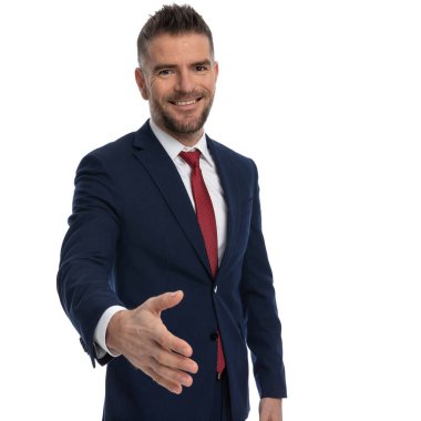 Genç işadamı elini kaldırıyor ve yüzünde bir gülümsemeyle dostça el sıkışmaya hazırlanıyor. 