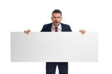 Çekici iş adamı bize boş bir ilan panosu gösteriyor ve beyaz sırt çantasından hayal kırıklığına uğruyor.