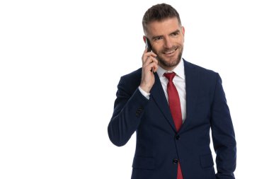 Yakışıklı iş adamı telefonda güzel bir konuşma yapıyor ve beyaz arka planda gülümsüyor.