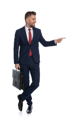 Genç yakışıklı iş adamı, bir çanta tutuyor ve kameraya gülümsüyor.