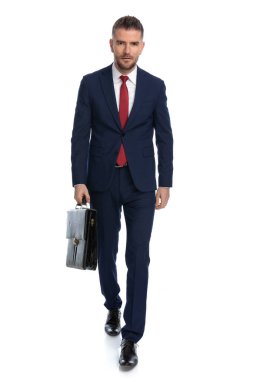 Genç işadamı gözlerinde sert bir tavırla yürüyor ve beyaz arka plana karşı bir dava yürütüyor.