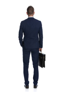 Donanma kıyafeti giyen ve beyaz stüdyo geçmişine karşı dava yürüten bir iş adamının arka görüntüsü.