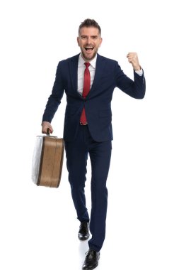 Çekici iş adamı iki tatil bileti kazanmasını ve beyaz arka planda bir bavul taşımasını kutluyor.