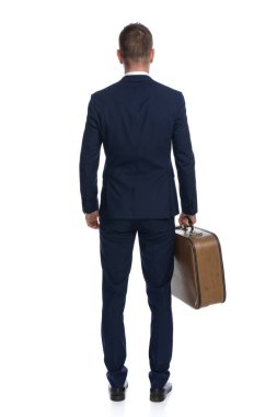 Bir iş adamının arkasını dönüp bavuluyla birlikte tatile çıkışının arka görüntüsü. 