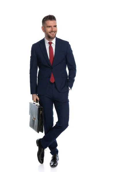 セクシーなビジネスマンがポケットに片手でケースを持ち笑顔で楽しい時間を過ごしてる — ストック写真
