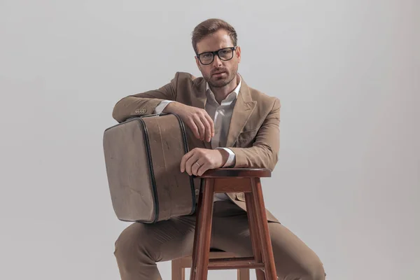 Çekici Adamı Elini Sandalyeye Dayayıp Bavulunu Gri Arka Planda Tutuyor — Stok fotoğraf